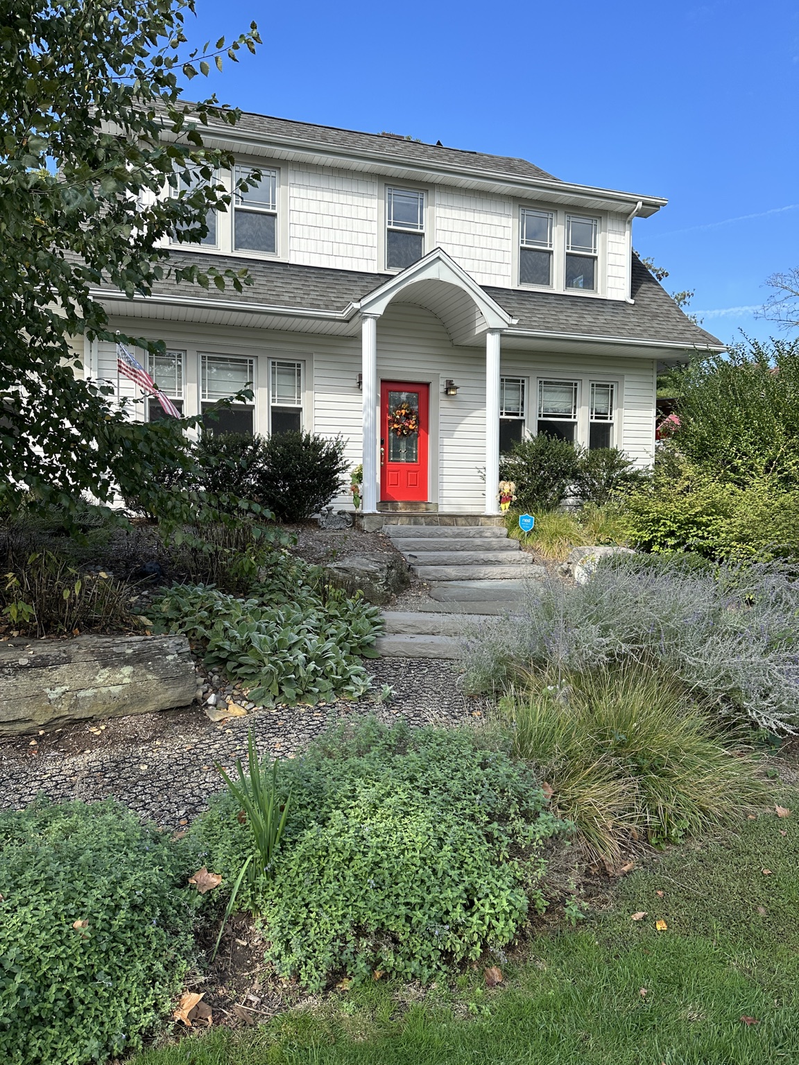 White home with a red front door and garden in Tappan